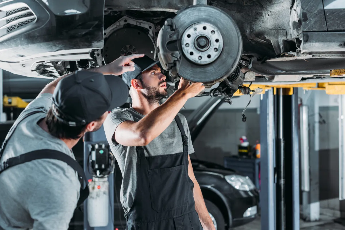 Auto Mechanics Repairing Car Without Wheel In Work